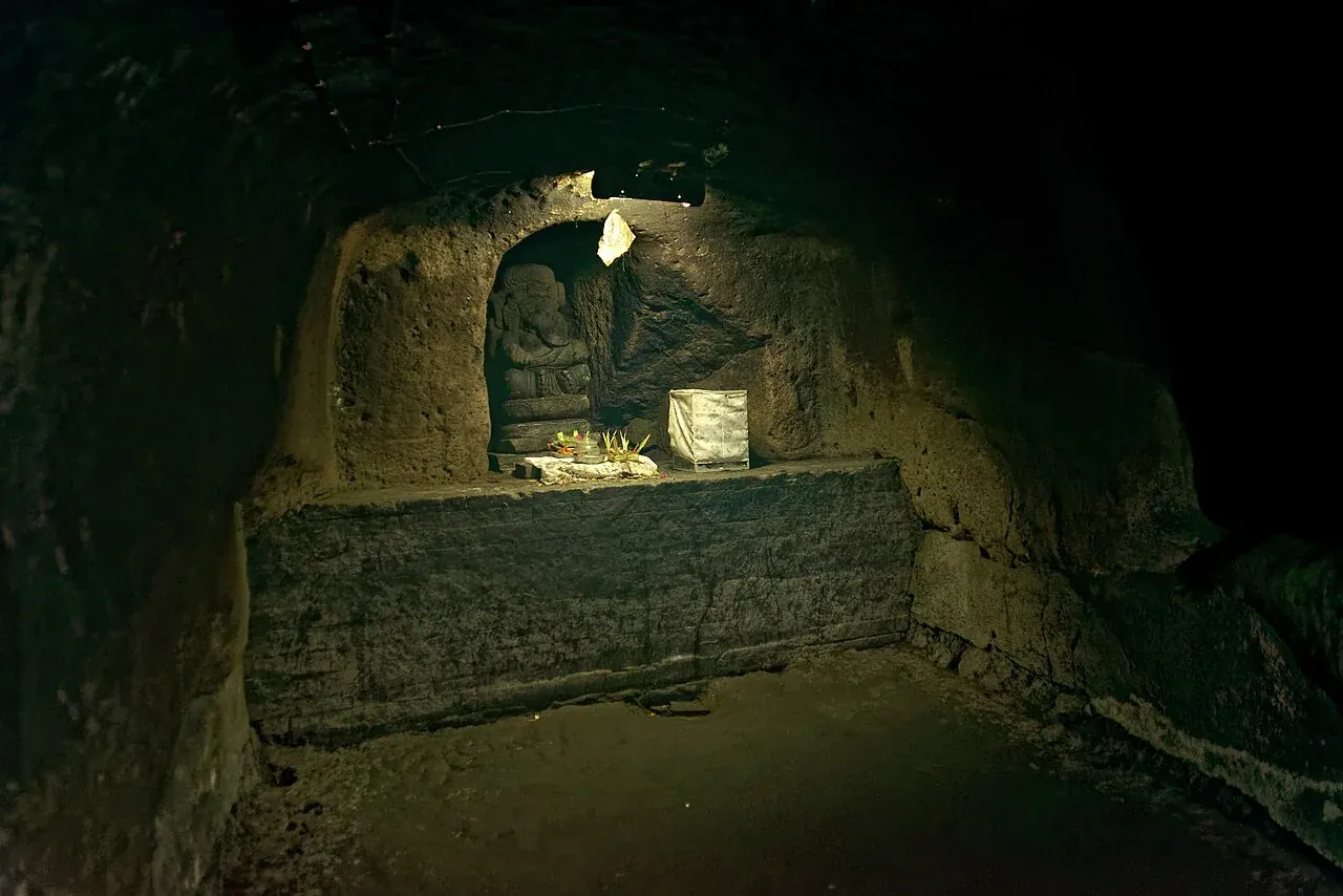 Het rotsinterieur en een stenen nis in Goa Gajah