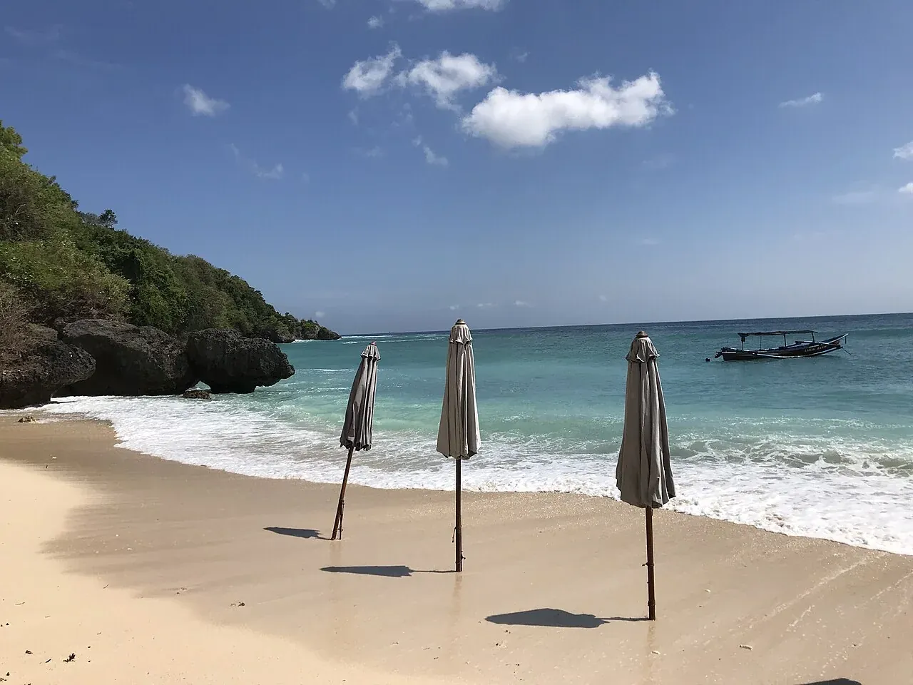 De zandbaai van Padang Padang met parasols en een rotswand
