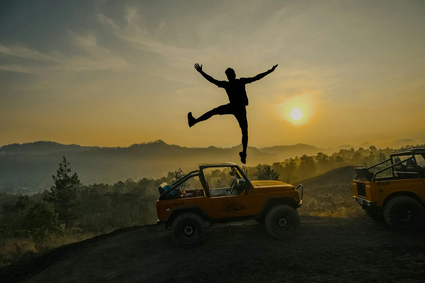 Silhouet boven een jeep bij Mount Batur in het ochtendlicht — Een jeep in het Baturgebied · sfeerbeeld