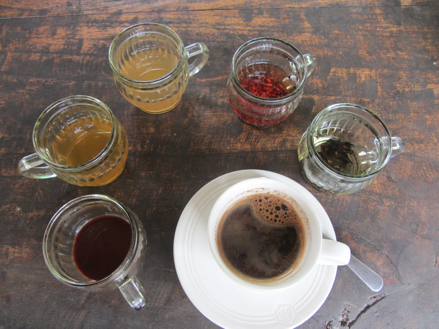 Kop koffie en verschillende proefdrankjes op een houten tafel op Bali — Koffie proeven op Bali · sfeerbeeld